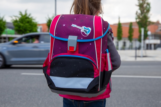 Kind mit Schulranzen an einer Straße Kind mit Schulranzen an einer Straße