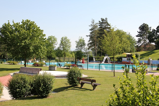 Kaiserstuhlbad mit Wiese und Pflanzen im Vordergrund und im Hintergrund das Schwimmbecken